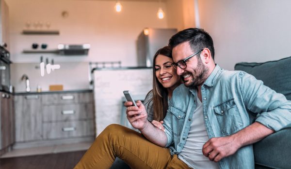 Couple looking at mobile phone at home.